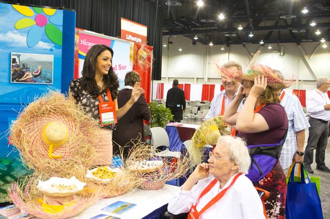 Farah Eslaquit, 2012 Miss Nicaragua, hands out straw hats at the Nicaragua Tourism Board booth during the 2013 AARP Convention on Thursday, May 30, 2013.